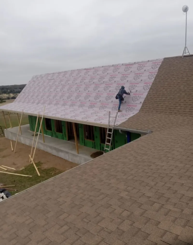 Worker preparing underlayment for a metal roof installation in Edna